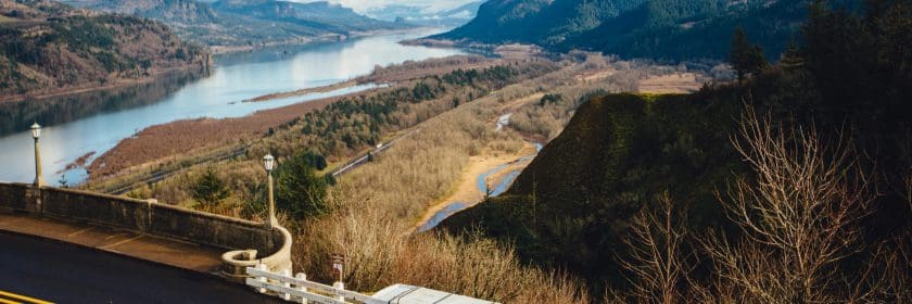 A van sits parked on the side of a road looking over a beautiful river valley, possibly with a driver trying to find something they forgot at the start of their long-distance move.