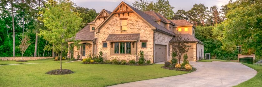 A beautiful home sits at the end of its driveway, lit by the afternoon sun.