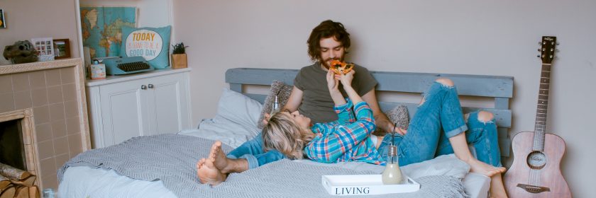 Couple eats pizza in bed