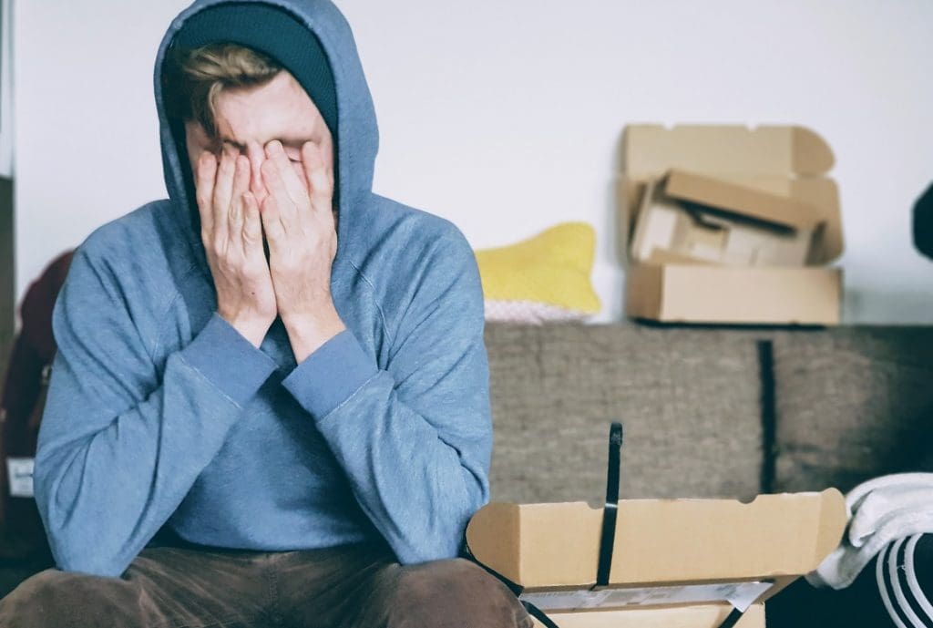 The Three P's to Help You Achieve A (Relatively) Stress-Free House Move 5 Young man holds his head in his hands with packing boxes in the background