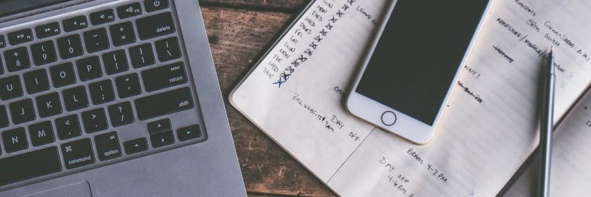 Computer, notebook, and phone on a desk