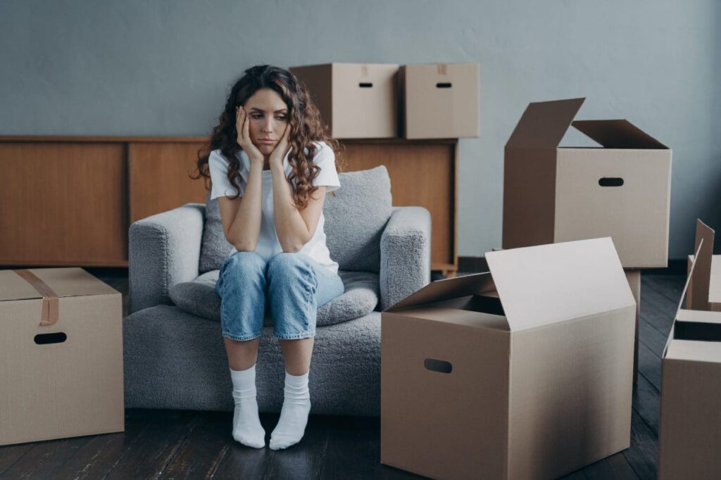 How to Choose the Right Moving Company in Ottawa, Kanata, and Barrhaven Without the Guesswork 3 tired sad girl sits with cartons feels unmotivated to pack things for moving hard relocation day