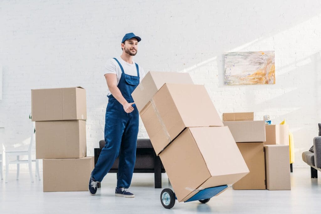 Why More Homeowners Are Combining Moving and Storage Services During Relocations in Stittsville, Kanata, and Laval 4 mover in uniform transporting cardboard boxes on X6KAQDN